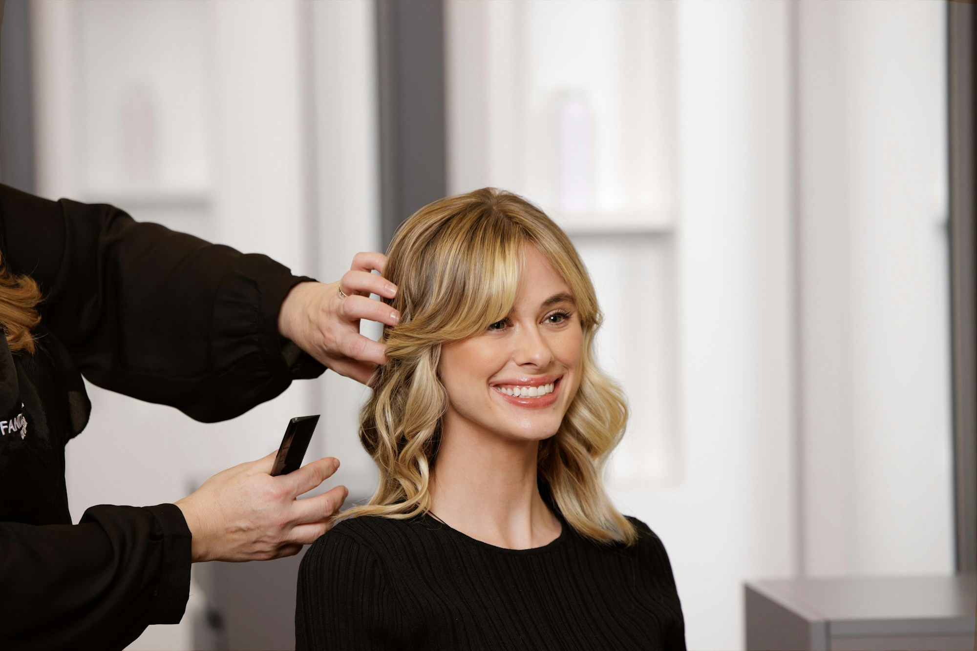 A stylist arranging a client’s softly textured blonde hair